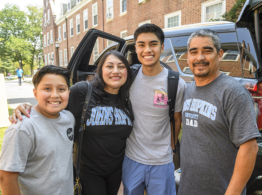 Family wearing Johns Hopkins apparel poses outside vehicle