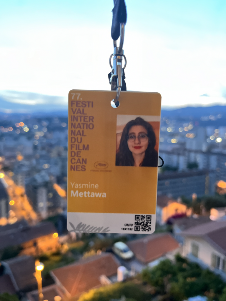 A badge reading "Festival International Du Film De Cannes" with a blurred city scape behind