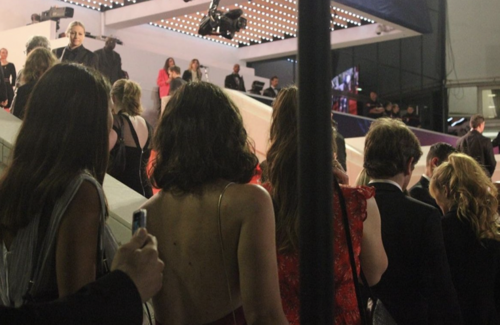 A line of people in formal wear in front of a red carpet staircase